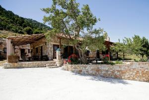 a house with a stone wall and a tree at Mike Omalos Houses in Omalos