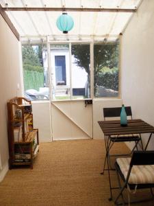 a room with a greenhouse with a table and a window at Epi-Centre in Préaux