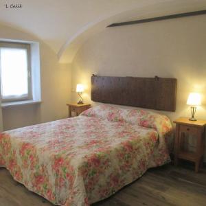 a bedroom with a bed with a floral bedspread at 'L Calié in Valdieri