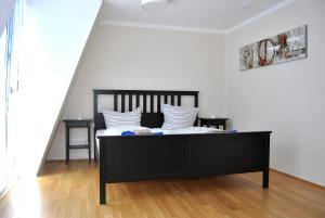 a bedroom with a black bed with white pillows at Trafford Sky Homes in Leipzig