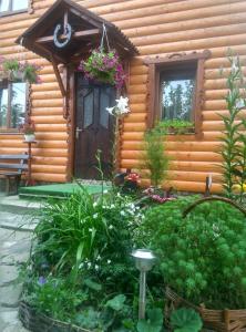 una cabaña de madera con un jardín de flores frente a ella en Teremok en Mykulychyn