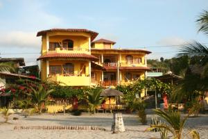 a large yellow building on a beach with palm trees at Hotel Cielo Azul in Atacames