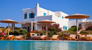 Una piscina con sillas y sombrillas al lado de un edificio. en Naoussa Bay Villas, en Naousa