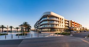 a large building with palm trees in front of it at Waterfront Apartments Marinaquays -Apt 221 and Apt 234 in Werribee South