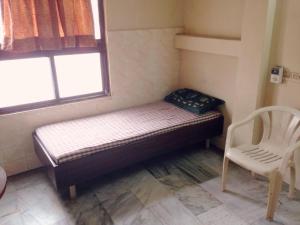 - un petit lit dans une chambre avec une fenêtre et une chaise dans l'établissement GP Mansion, à Chennai