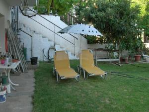 twee stoelen en een paraplu in een tuin bij Apartment Next to the Sea in Poseidonia in Posidhonía