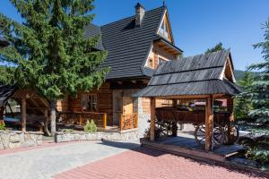 ein Blockhaus mit einem Pferdewagen davor in der Unterkunft Rezydencja Bambi in Zakopane