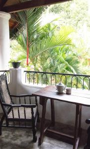 a table and a chair on a balcony with a palm tree at Villa Taprobane in Negombo