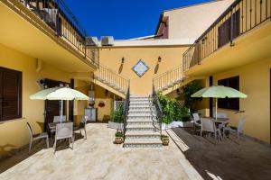 a building with stairs and tables and chairs and umbrellas at Appartamenti il Patio in San Vito lo Capo