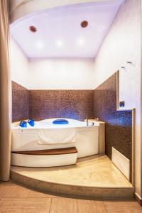 a bathroom with a tub and a tile wall at Hotel Flora in Noto