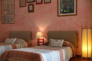 2 camas en una habitación con paredes rosas en B&B Casa Degli Ulivi, en Negrar