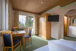 a hotel room with a bed and a desk and a table at Landgasthof Pfarrwirt in Thiersee