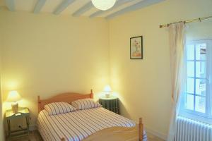 ein Schlafzimmer mit einem Bett, zwei Lampen und einem Fenster in der Unterkunft Les Hauts de Chaume in Génillé