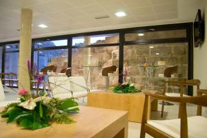 Habitación con mesas, sillas y pared de piedra. en Hotel MedinaSalim, en Medinaceli