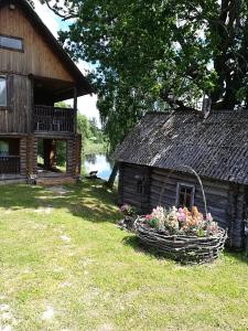 a barn with a basket of flowers next to a building at Pie Ozola in Repši