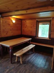 un banco de madera en una cabaña con ventana en Pie Ozola, en Repši