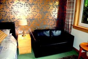 a bedroom with a black leather chair against a wall at Torcroft Lodges in Drumnadrochit