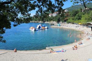 people on a beach with a boat in the water at Apartment Tominovic in Opatija