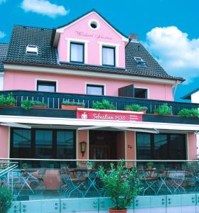 a pink building with tables and chairs in front of it at Gästehaus Garni Sebastian 1520 in Rech