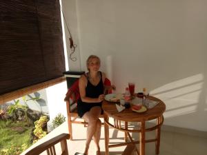a woman sitting at a table with a glass of wine at Minory Guesthouse in Amed