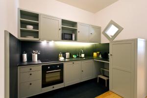 uma cozinha com armários brancos e um forno com placa de fogão em Trait House no Porto