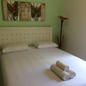 a bed with two rolled towels on top of it at Suites Praia de Pernambuco in Guarujá