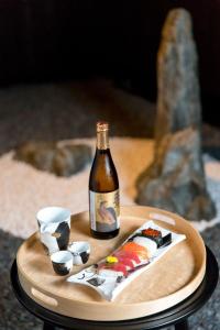 una botella de vino y sushi en una bandeja de madera en R&Run Kyoto Serviced Apartment & Suites, en Kioto