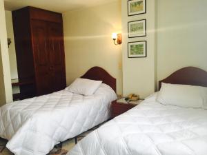 two beds sitting next to each other in a room at Hotel Azuay in Duitama
