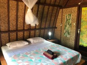 a bedroom with a bed with a bag on it at Meno Madia Bungalows in Gili Meno