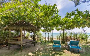 會安的住宿－安邦海洋之家別墅，两把蓝色椅子和一把伞下的长凳