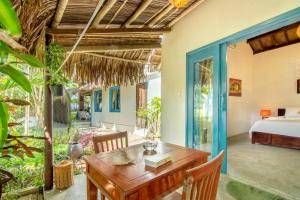 a dining room with a bed and a wooden table at Ocean House An Bang in Hoi An