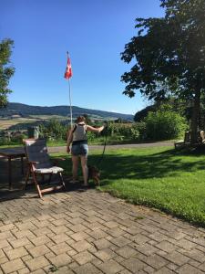 a woman with a dog on a leash next to a chair at BnB im Waldhof in Schneisingen