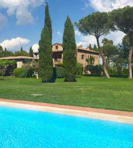a house with trees and a swimming pool in front at Fattoria Cirene in Follonica