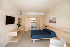 a small room with a blue bed and a tv at Cave Bianche Hotel in Favignana