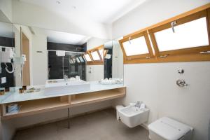 a bathroom with a sink and a toilet and a mirror at Cave Bianche Hotel in Favignana