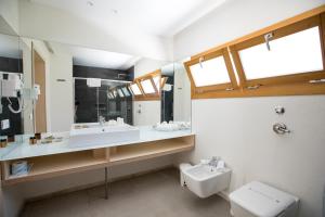 a bathroom with a sink and a toilet and a mirror at Cave Bianche Hotel in Favignana