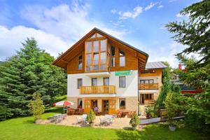 a large house with a deck and a yard at Pension Karolína in Špindlerův Mlýn