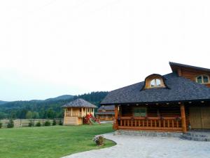 a log cabin with a playground and a house at Cabana Goralilor in Mănăstirea Humorului