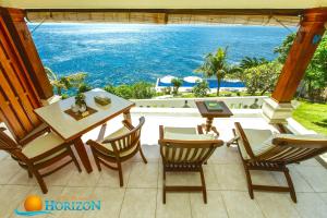 un patio con mesa, sillas y el océano en Villa Infinite Horizon, en Amed