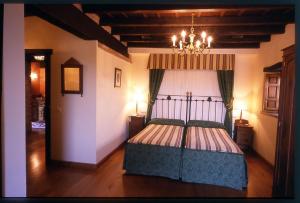 a bedroom with a bed with a chandelier in it at El Ama De Llaves in Hontoria +11 photos