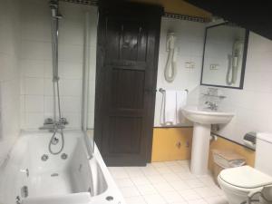 a bathroom with a tub and a toilet and a sink at El Ama De Llaves in Hontoria