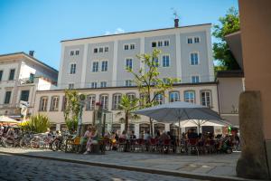 eine Gruppe von Personen, die vor einem Gebäude an Tischen sitzen in der Unterkunft Art Hotel & Hostel in Passau