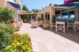 a patio with chairs and tables and flowers at Grand Hotel Moriaz in Le Lavandou