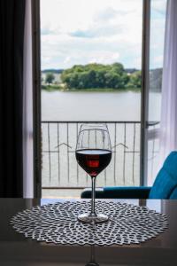 a glass of wine sitting on a table in front of a window at Apartamenty Na Skarpie in Ełk