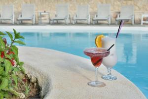 zwei Cocktails auf einem Tisch neben einem Pool in der Unterkunft Ionion Star Hotel in Lefkada Town