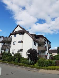 a white apartment building with balconies on a street at Harzhome in Herzberg am Harz