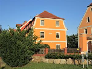 uma casa laranja com uma cerca e uma árvore em Rittergut zu Groitzsch em Jesewitz