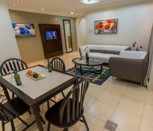 uma sala de estar com uma mesa e cadeiras e um sofá em Baisan Suites Al Jubail em Al Jubail