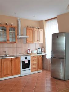 La cuisine est équipée d'armoires en bois et d'un réfrigérateur en acier inoxydable. dans l'établissement Apartament Mikołajki, à Mikołajki
