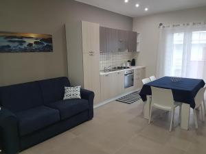 ein Wohnzimmer mit einem blauen Sofa und einem Tisch in der Unterkunft The Sweet Home of Milazzo in Milazzo
